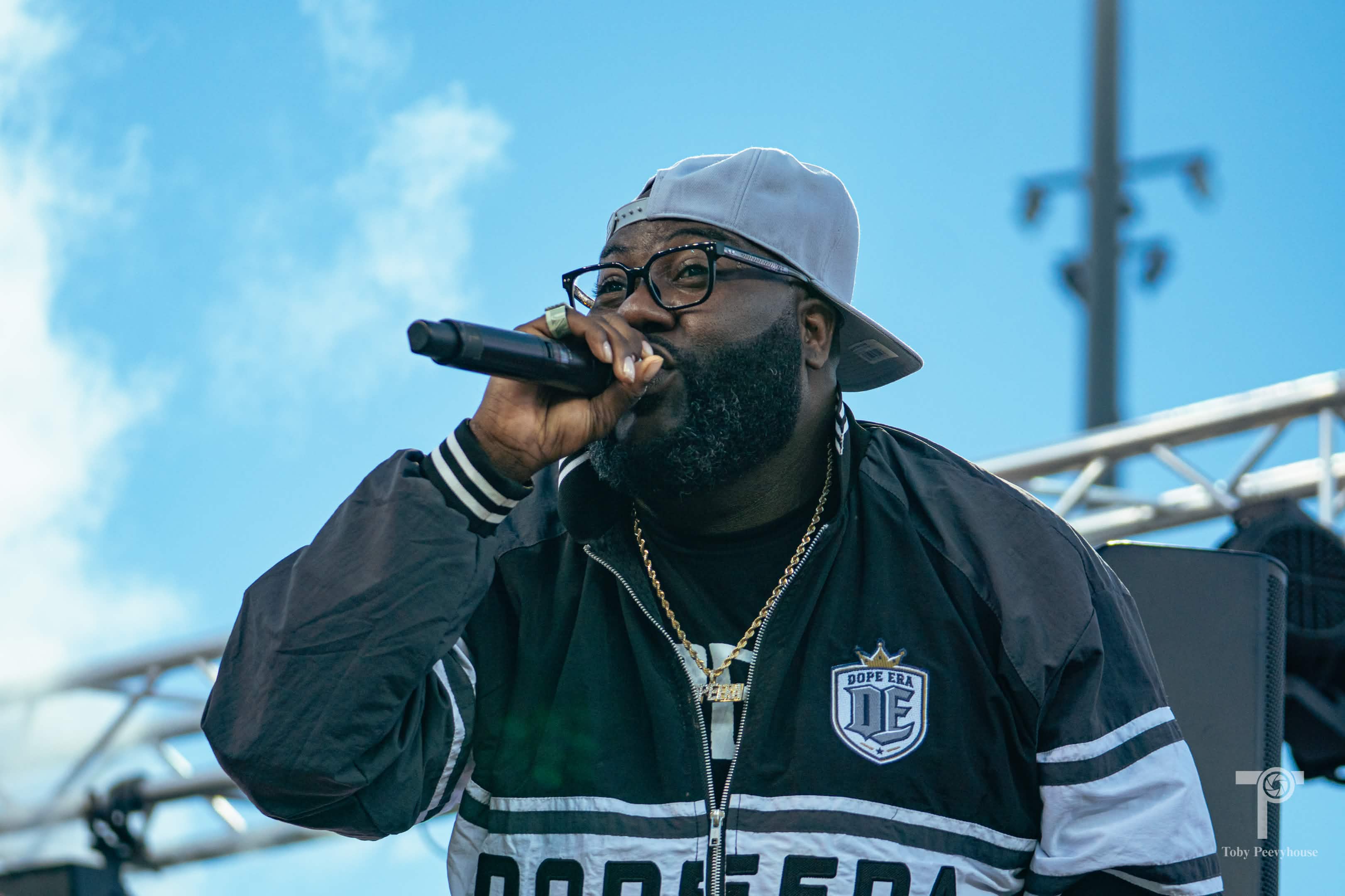 A hip-hop artist performing on stage beneath a blue sky.